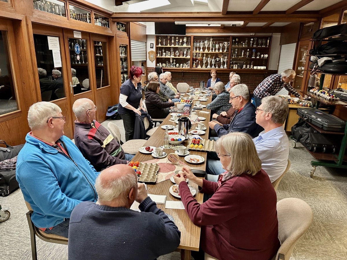 Gruppe von Senioren am gedeckten Tisch beim Ostereierschießen