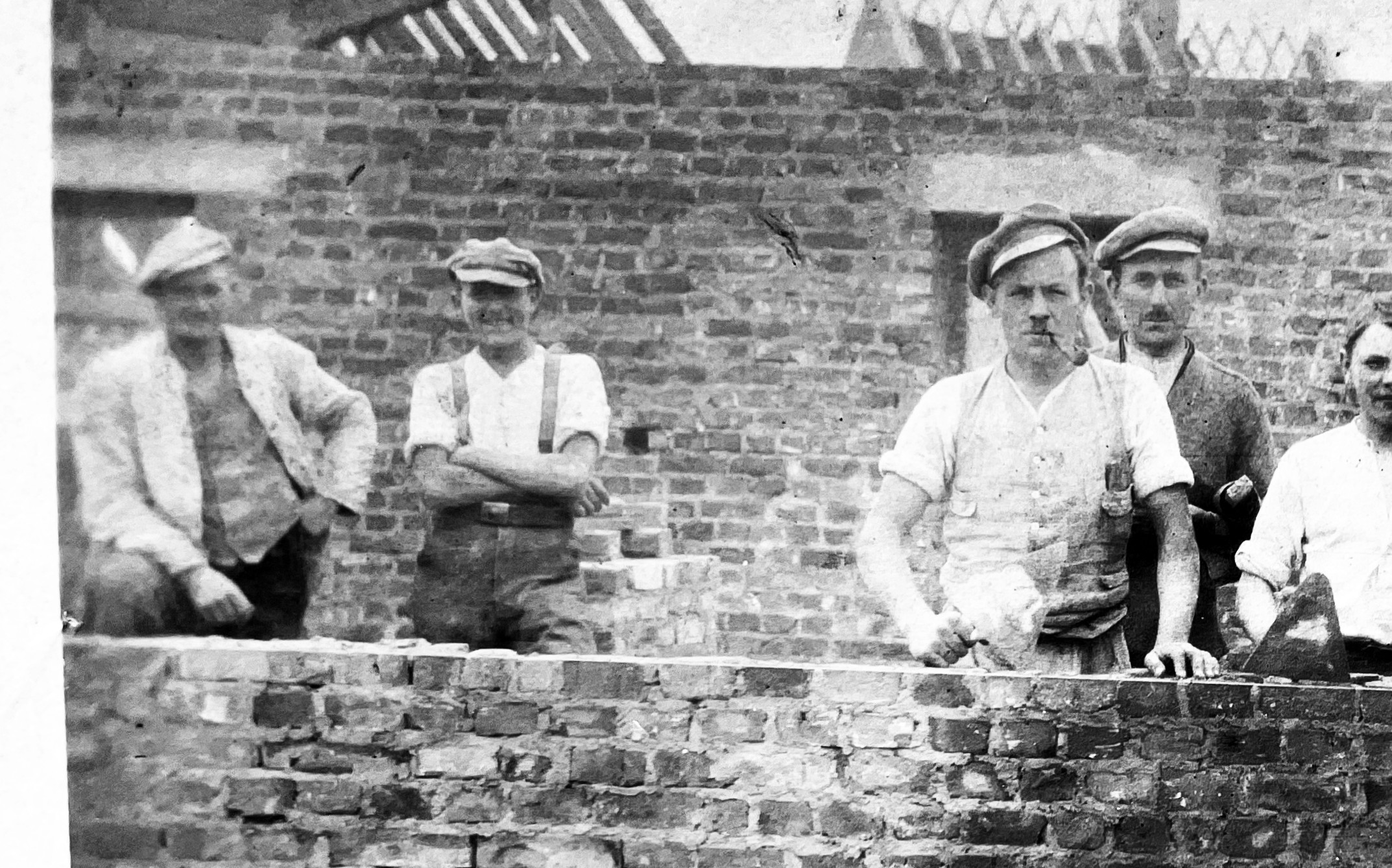 Bauarbeiter aus den 1920er Jahren vor einem Haus im Rohbau, vergrößert links
